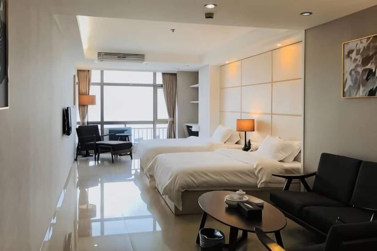 A hotel room with a bed, a sofa, a desk, and a chair.