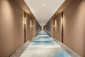 A long hallway with a patterned carpet, wall sconces, and a ceiling with recessed lighting. - Century Seaview Hotel (Nan'ao County)
