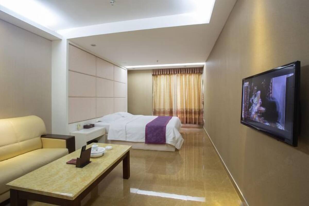 A hotel room with a bed, a sofa, a TV, and a desk.