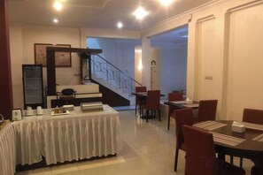 A hotel dining area with a staircase, a table set with plates, and chairs. - Monika Hotel (Rantepao)