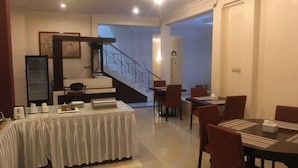 Un espace repas avec une table couverte, des chaises et un escalier menant à un niveau supérieur.