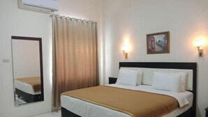 Une chambre d’hôtel avec un lit, un miroir, un tableau au mur et une fenêtre avec des rideaux.