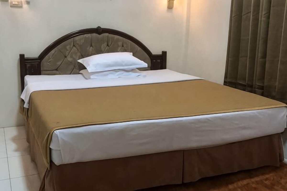 A bed with a headboard, white bedding, and a brown skirt.