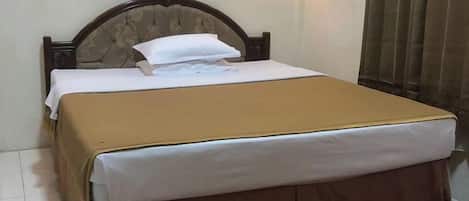 Una cama bien hecha, con cabecera marrón, ropa de cama blanca y falda marrón.