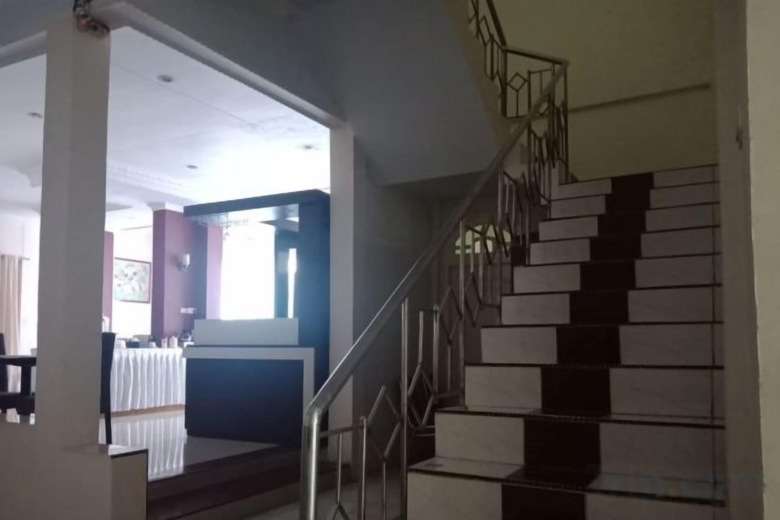A staircase with metal railings and a landing area with a table and chairs.