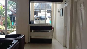 A hallway with a bench, a door, and a window with a view of a parked car and greenery outside.