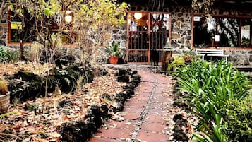 Traditional Japanese-style entrance with a sliding door, surrounded by lush greenery and a brick pathway.