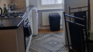 Una cucina compatta con piano cottura a gas, pensili bianchi, una sedia nera e un tappeto decorato.