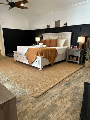 A bedroom with a bed, bedside tables, a ceiling fan, and a dark wall. - The Phoenix Estate-Luxury Modern Farmhouse Getaway (Palm Beach Gardens)
