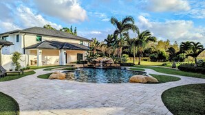 Une maison avec une piscine, une terrasse et un jardin agrémenté de palmiers.