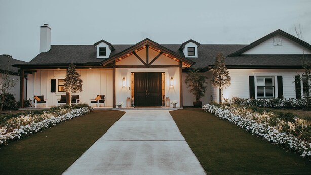 Une maison à deux étages avec un porche à l’avant, un garage et une pelouse bien entretenue.