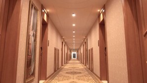 A long, narrow hotel corridor with wooden doors on either side, a patterned carpet, and recessed lighting on the ceiling. - Vienna Hotel (Suzhou Industrial Park, Yangcheng Lake, Fashion Stage) (Suzhou)