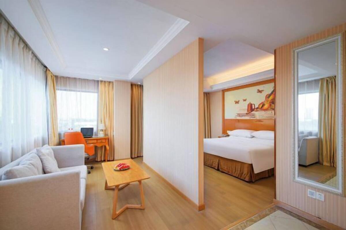 Una habitación de hotel con una cama, un escritorio, una silla, un sofá y un espejo.