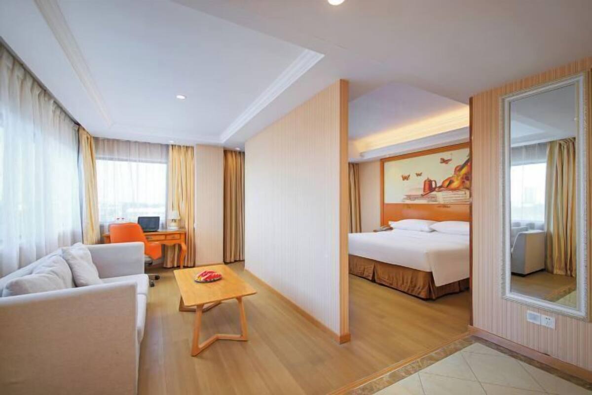 Habitación de hotel con cama, escritorio, silla, sofá y una pequeña mesa.