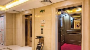 A hotel lobby with a red carpet, an elevator, and a wall-mounted information board. - Vienna Hotel (Suzhou Industrial Park, Yangcheng Lake, Fashion Stage) (Suzhou)