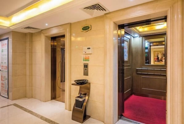 A hotel lobby with a red carpet, an elevator, and a wall-mounted information board. - Vienna Hotel (Suzhou)