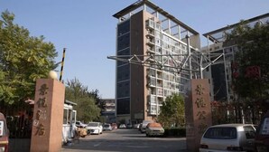 Un edificio de varios pisos con un diseño arquitectónico moderno, que cuenta con un atrio central y varios balcones.