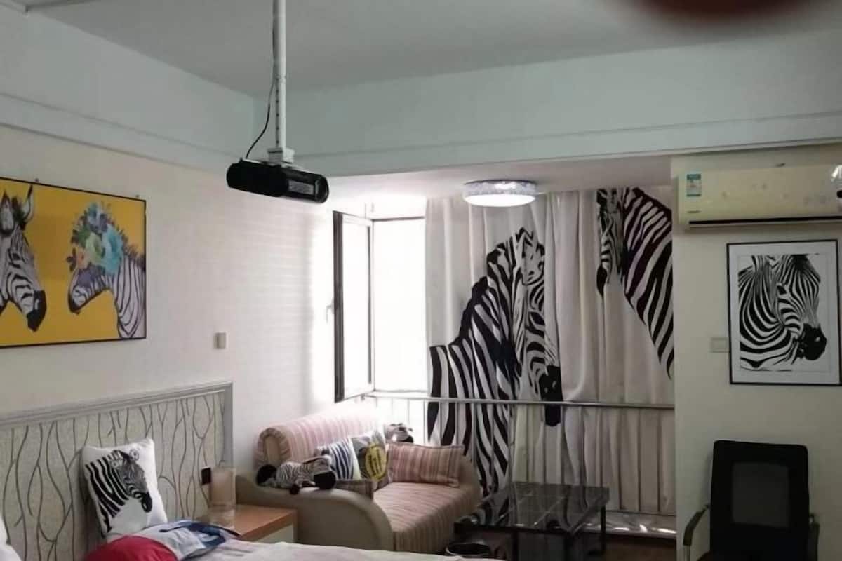 Ein Zimmer mit Bett, Sofa, Tisch und Projektor.