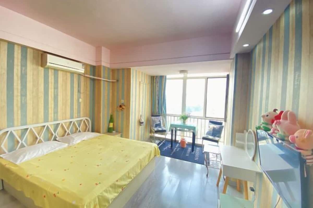Ein Hotelzimmer mit Bett, Schreibtisch, Stuhl, kleinem Tisch und einem Balkon mit Blick.