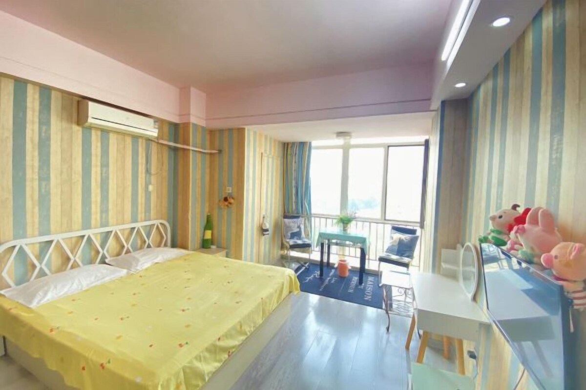 A hotel room with a bed, a desk, a chair, a table, and a balcony with a view.