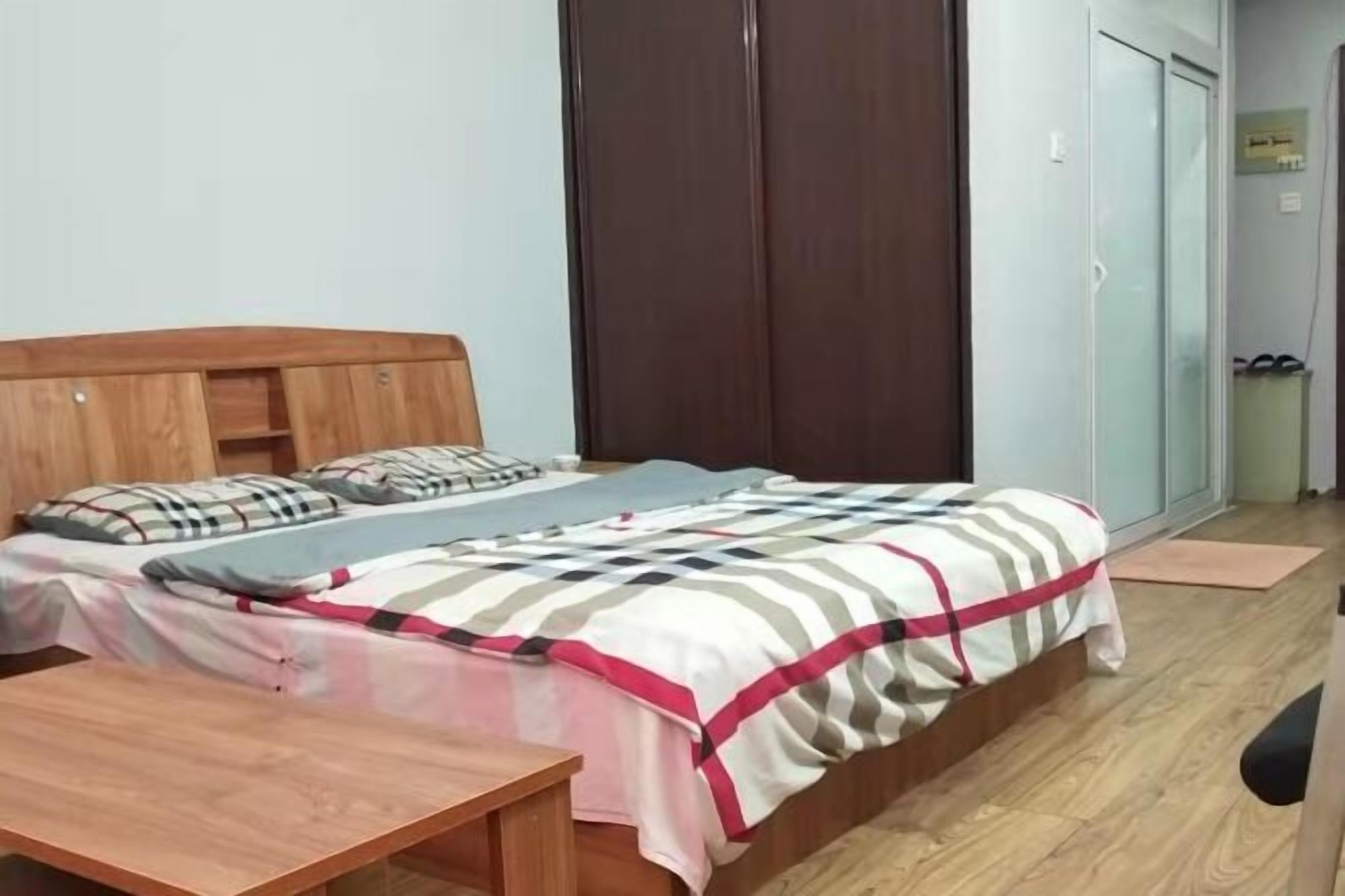 A bedroom with a bed, a wooden headboard, a bedside table, and a wardrobe.