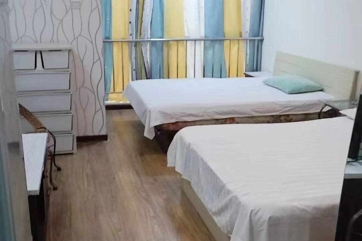 Ein Hotelzimmer mit zwei Betten, einem Schreibtisch und einem Kleiderschrank.