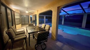 A covered outdoor area with a pool, a table, and chairs. - Updated luxury 4 Bed W/ KING Bed, FREE Heated Pool, Central Location (Port Charlotte)