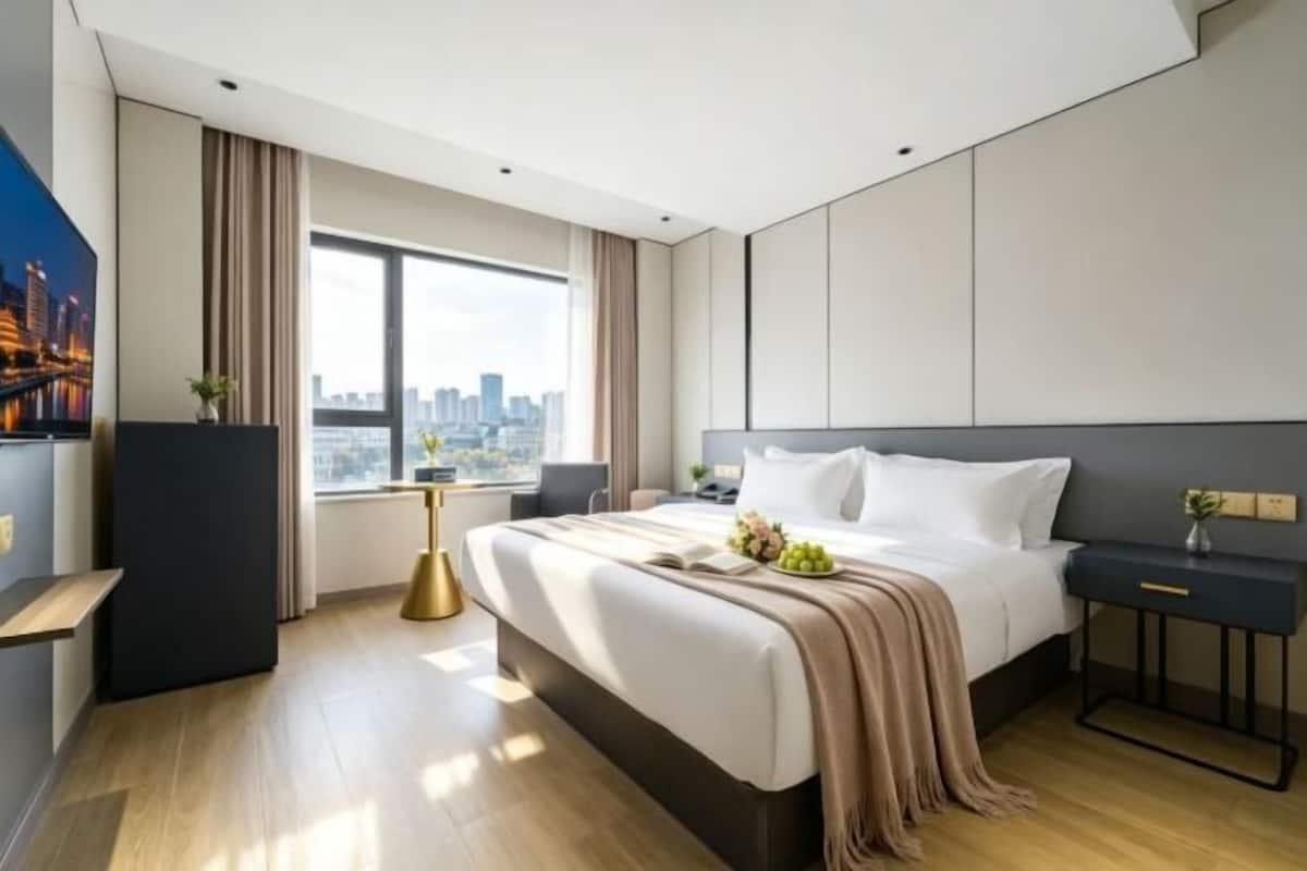 Ein modernes Hotelzimmer mit einem großen Bett, einem Schreibtisch, Blick auf die Stadt und einem Stadtbild an der Wand.