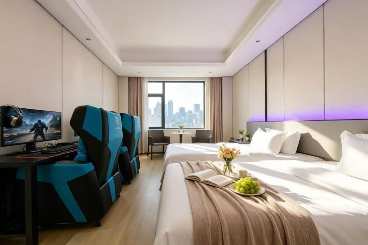 A hotel room with a bed, a desk with a computer, a TV, and a city view.