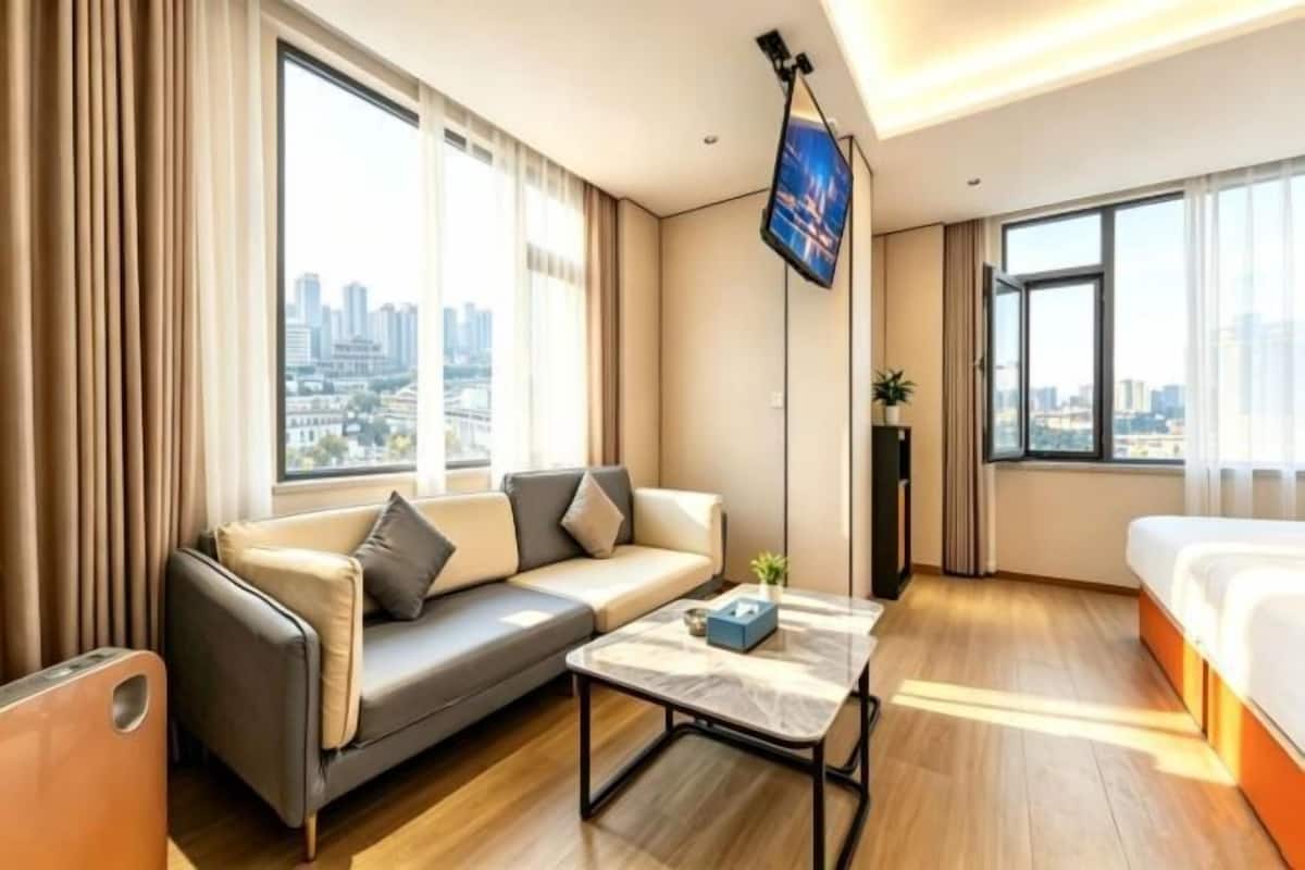 Ein modernes Hotelzimmer mit einer Couch, einem Bett, einem Couchtisch und Blick auf die Stadt.