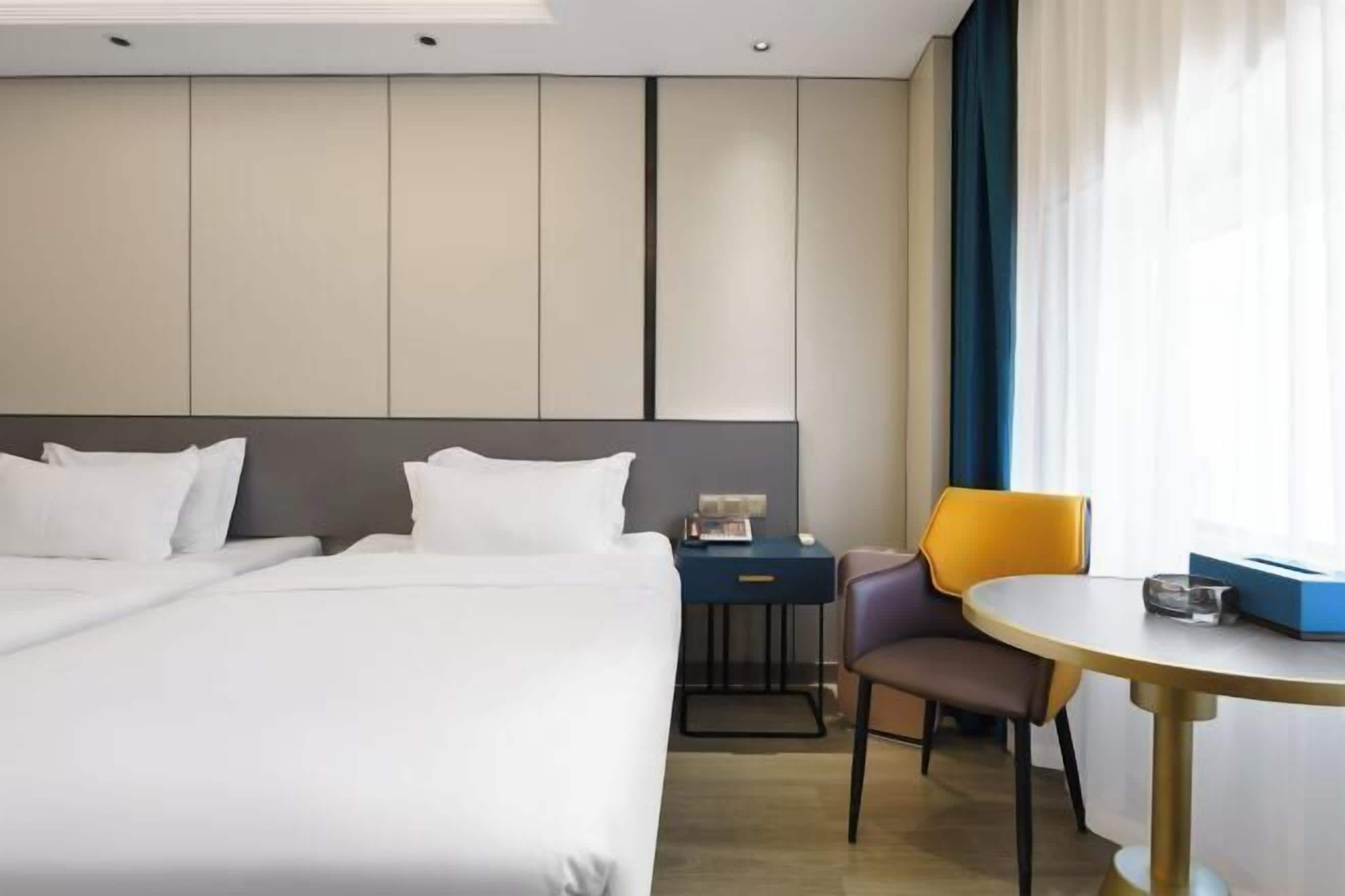 A hotel room with a large bed, a desk, a chair, and a small table.