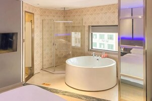 Un baño moderno con una bañera grande, ducha a ras de suelo y cama con vistas a la ciudad.