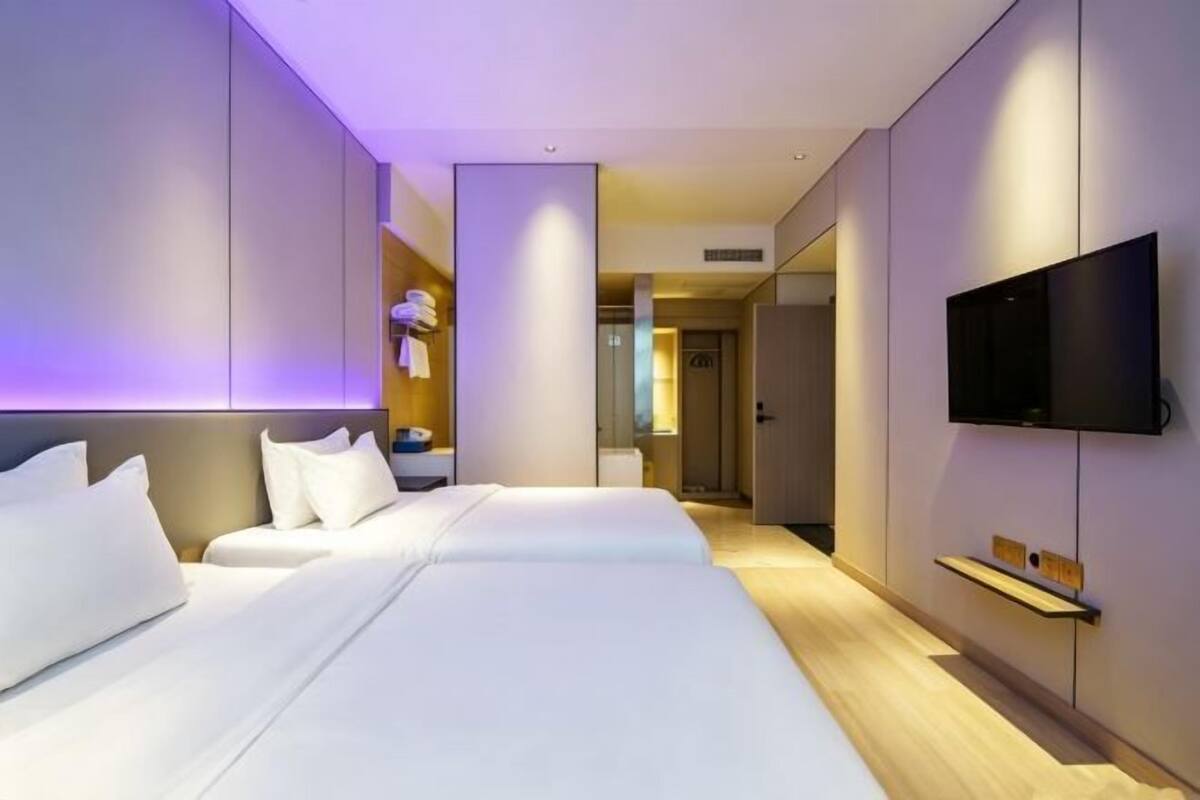 Ein modernes Hotelzimmer mit einem großen Bett, einem Flachbildfernseher und einem begehbaren Kleiderschrank.