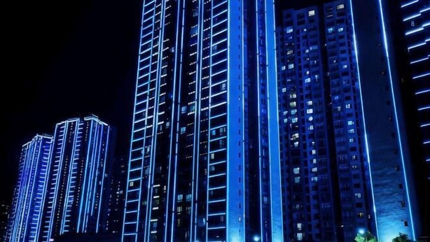 A high-rise building with multiple floors, illuminated by blue lighting. - Qiangxing Inn (Chongqing)