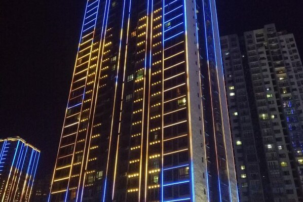 A high-rise building with illuminated windows and a modern architectural design.