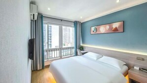 A hotel room with a bed, a TV, a window with curtains, and a wall-mounted artwork. - Qiangxing Inn (Chongqing)