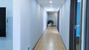 A modern hallway with light-colored walls and wooden flooring, leading to a room with a blue accent wall. - Qiangxing Inn (Chongqing)