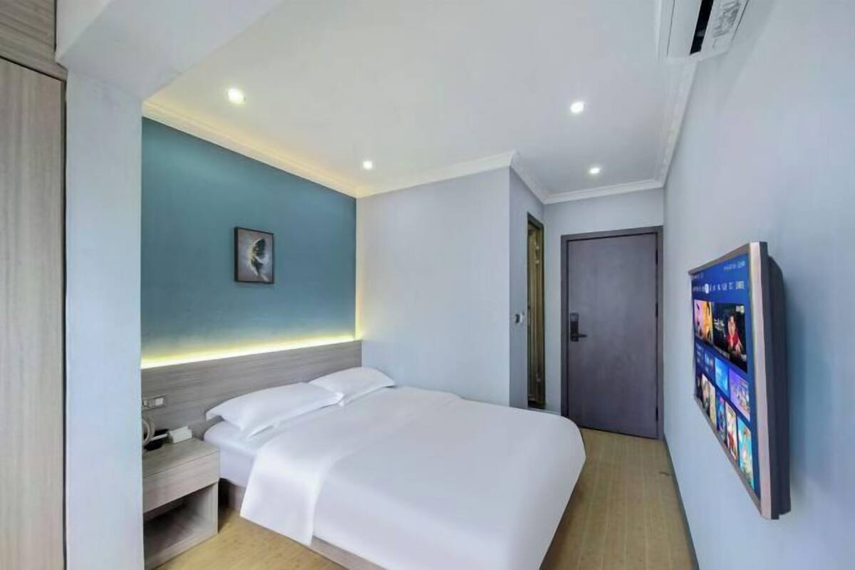 Una habitación de hotel moderna con cama, mesita de noche y un marco digital para fotos.
