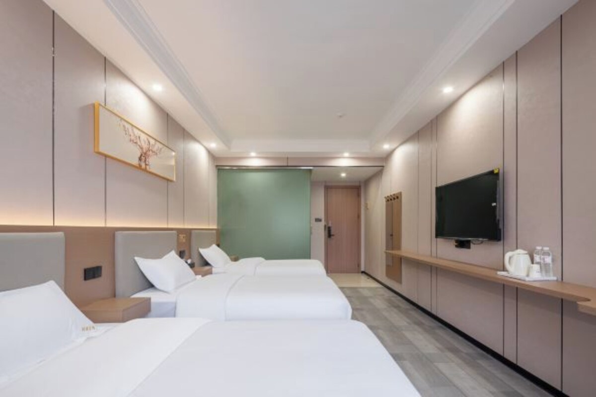 A hotel room with two beds, a television, and a small kitchenette area.