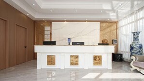 Un comptoir d’accueil avec un décor en marbre, des panneaux en bois et un grand vase.