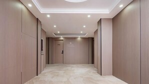 Un couloir doté d’un sol à motifs, d’un éclairage encastré et d’une porte sur laquelle est apposée une pancarte.