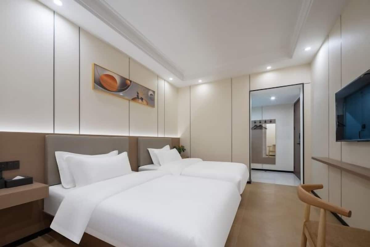 A modern hotel room with a large bed, bedside tables, a flat-screen TV, and a painting on the wall.