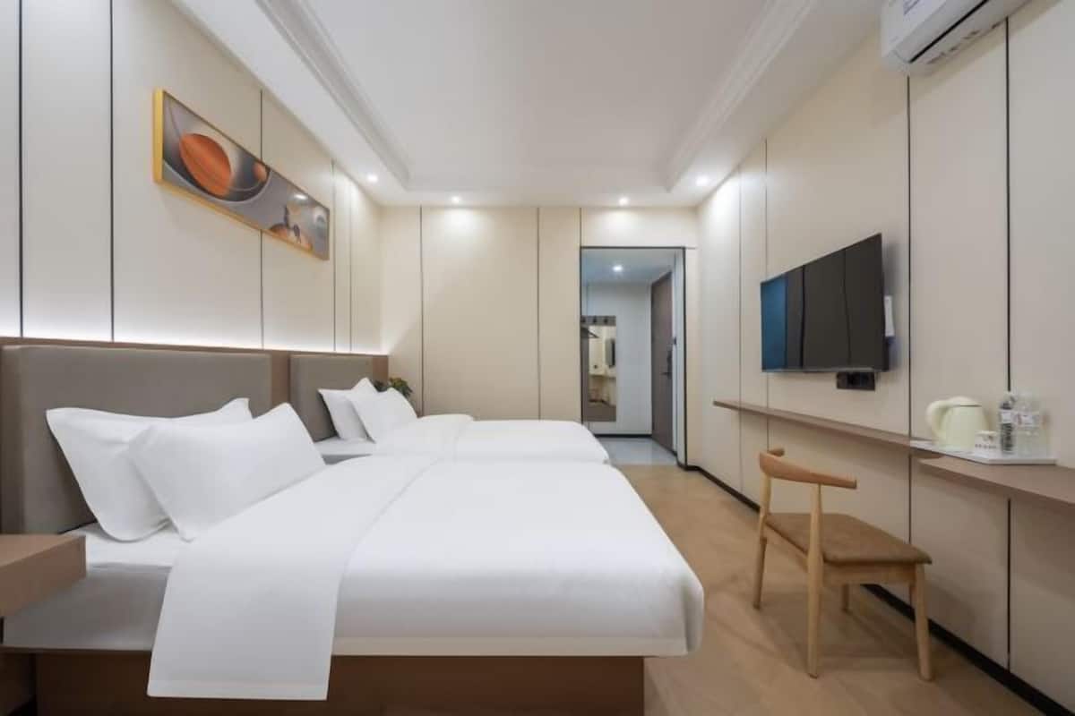 A hotel room with a bed, a TV, a desk, and a chair.