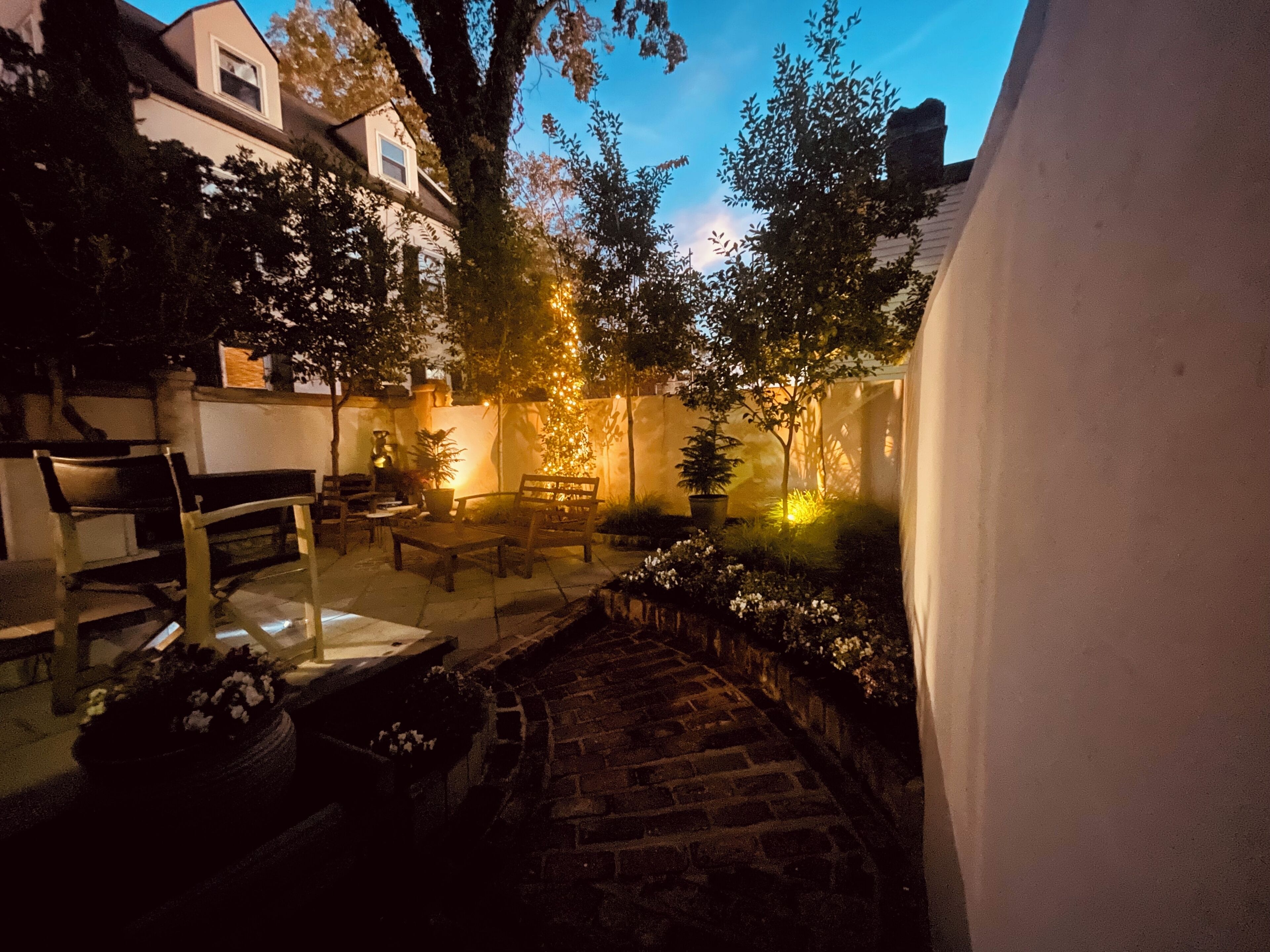 Un cortile con un vialetto in mattoni, mobili in legno e piante in vaso.