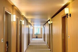 A hotel hallway with doors on both sides, a carpeted floor, and wall-mounted lights. - Wanli Hotel (Qinzhou)
