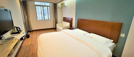 A hotel room with a bed, a TV, a desk, and a window.