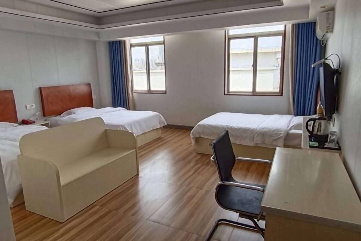 A hotel room with two beds, a sofa, a desk, and a chair.