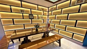 Un intérieur moderne avec une table et des bancs en bois, des panneaux muraux éclairés et des tableaux encadrés.