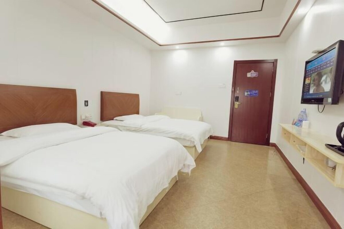 Una habitació d'hotel amb dos llits, televisió, escriptori i una porta.