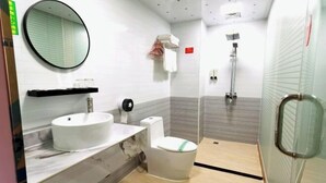 Une salle de bain moderne avec un grand miroir rond, un lavabo, des toilettes et un espace douche.